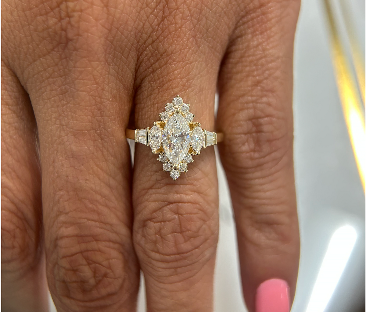 Marquise engagement ring with diamond accents worn on a hand