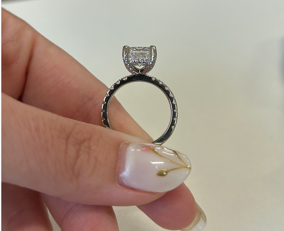 Side view of a princess-cut engagement ring with diamond accents