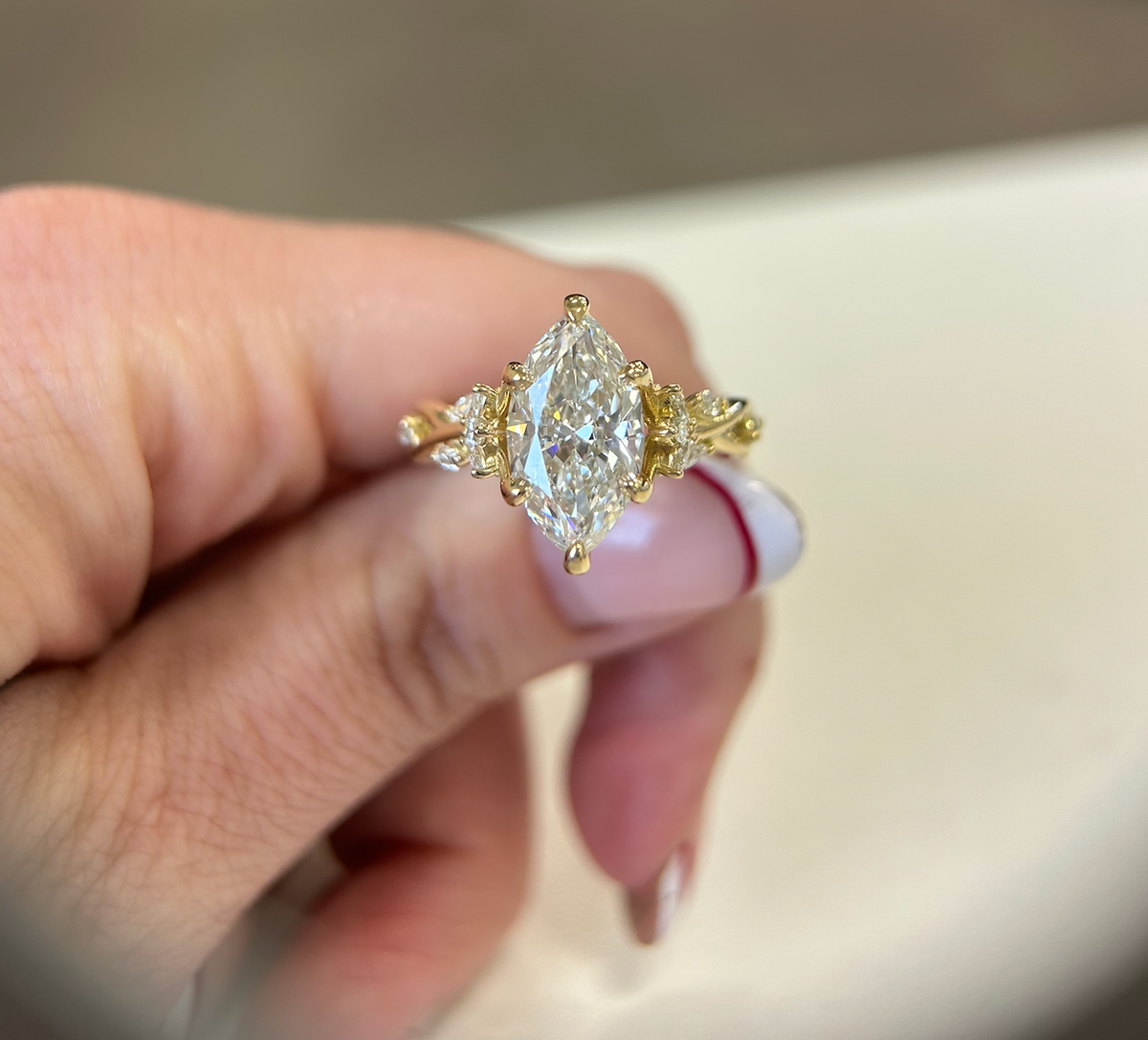 Marquise diamond engagement ring in yellow gold with decorative side stones