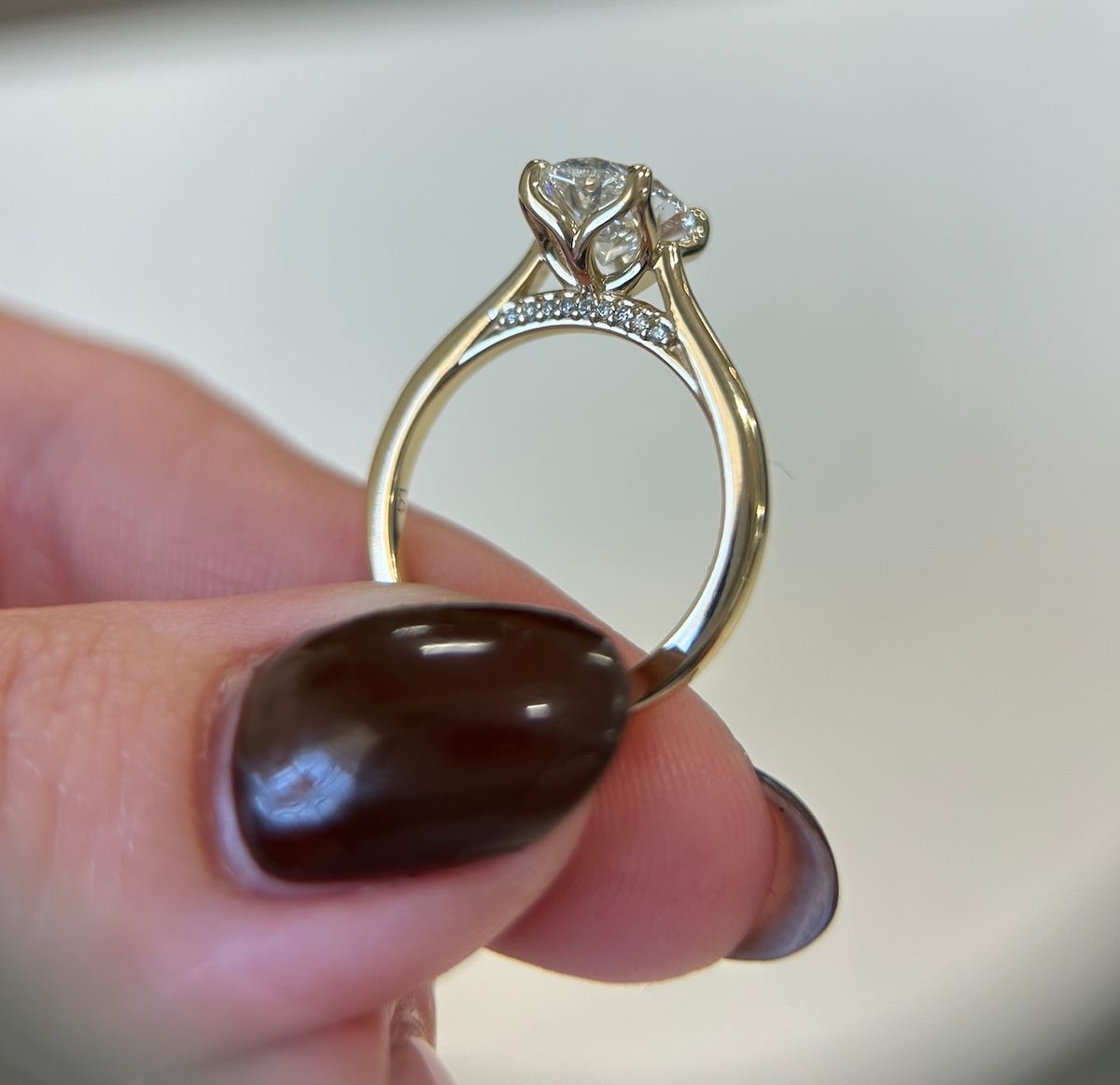 Profile of an oval diamond ring with a yellow-gold setting and diamond accents